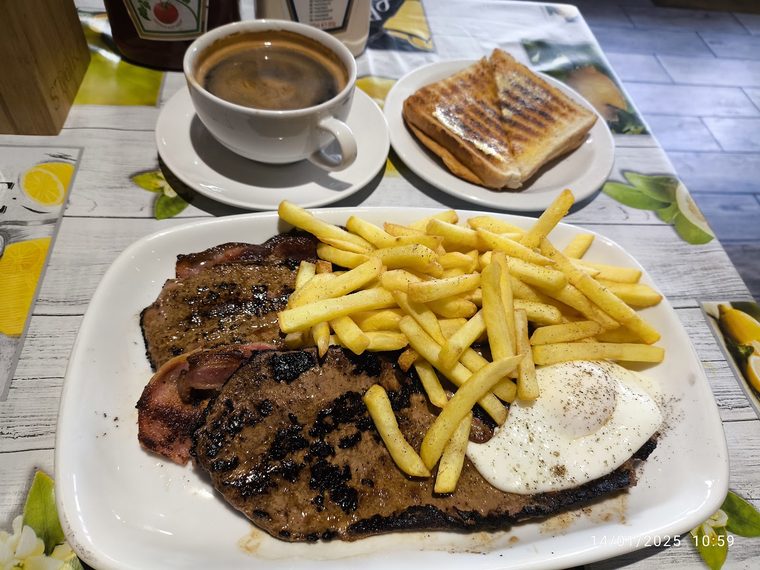 Mixed grill with steak, bacon, chips and a fried egg. Crop the burned-in caption text off the edge.