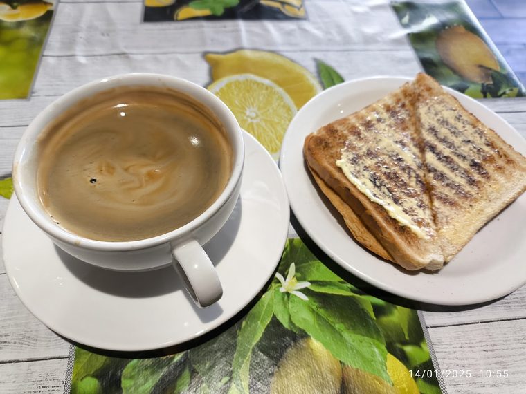 A toasted panini with a cup of coffee. Crop the burned-in caption text off the edge.